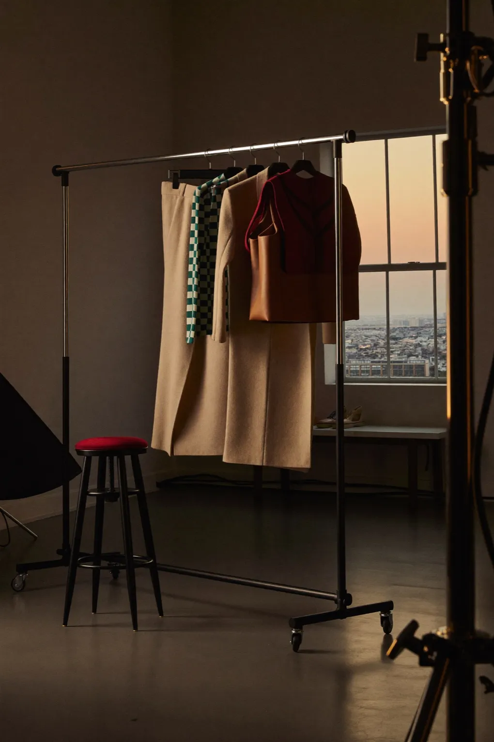 Studio in der Abenddämmerung mit Kleiderstange, Hocker und Stativ.