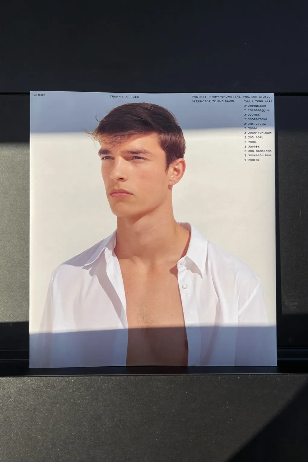 Gedruckte Sedcard eines jungen Models auf einer dunklen Fläche.