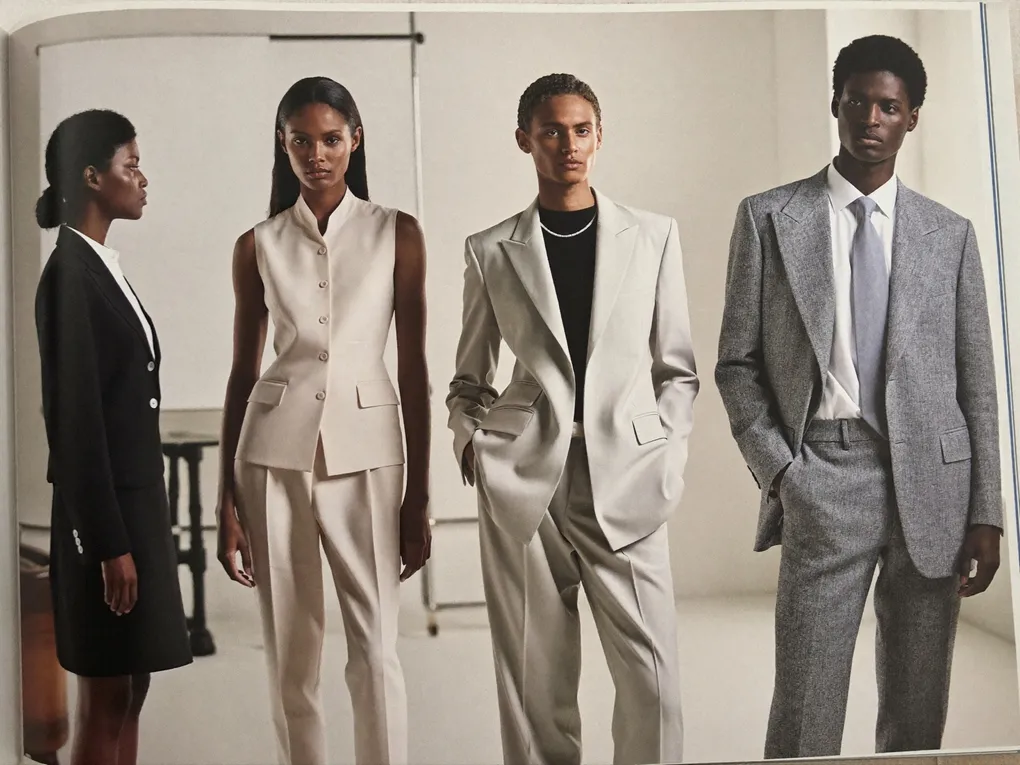 Vier Models in Anzügen stehen vor hellem Studiohintergrund nebeneinander.
