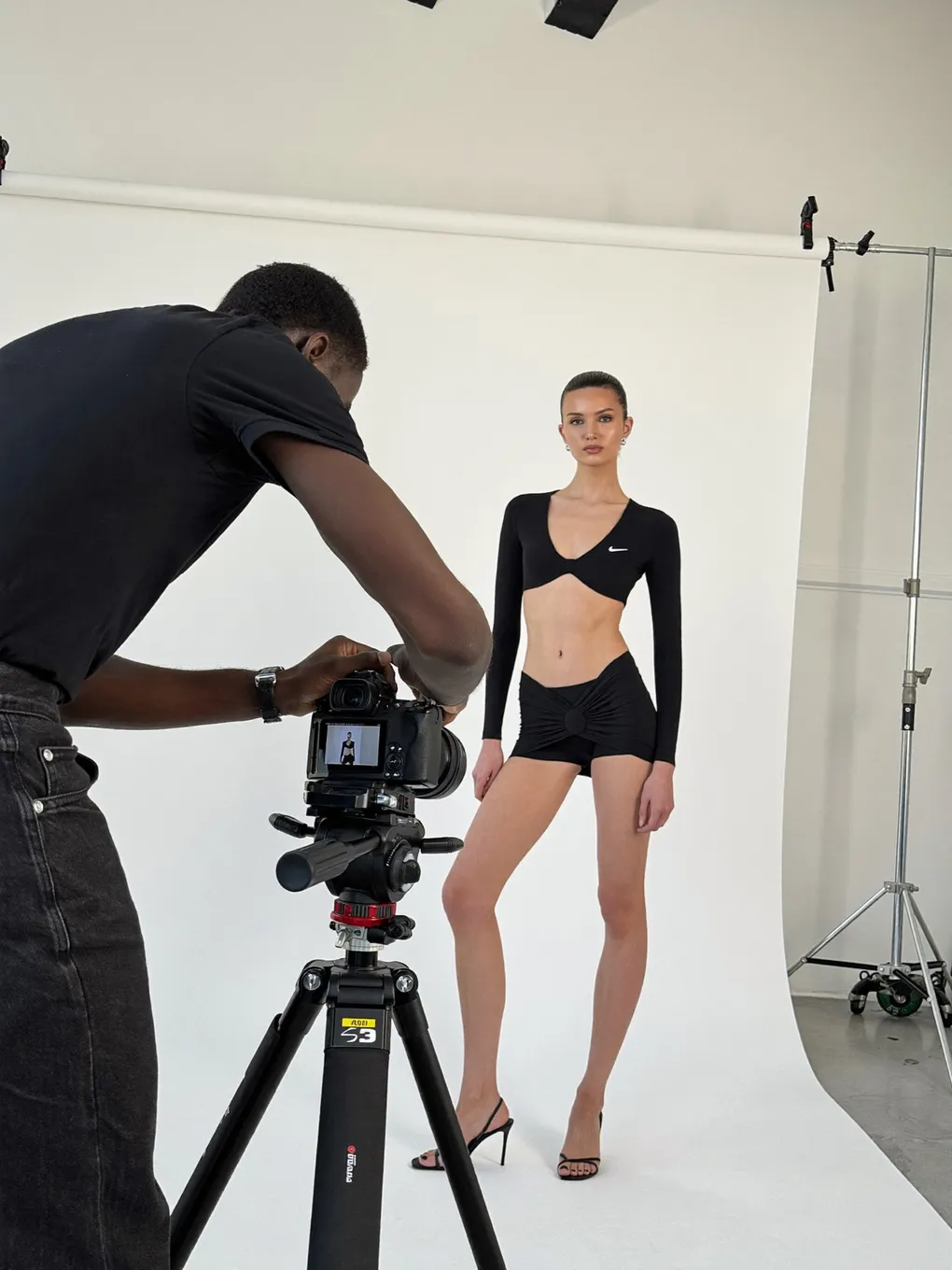 Fotograf fotografiert ein Model vor weißem Hintergrund im Studio.